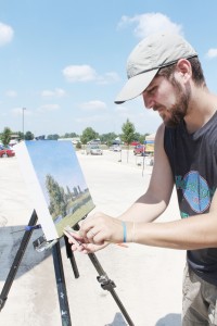 Photo by Keith Stewart Local artist Benjamin Cohan puts the finishing touches on a scene outside of the Green Mill Village Best Western in Arcola Saturday during the Taste of the Prairie event.