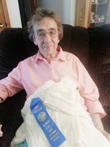 Photo Submitted Sullivan resident Donna Jean is seen here with her first place ribbon she earned at the state fair for her knitted baby sweater, hat, and blanket.