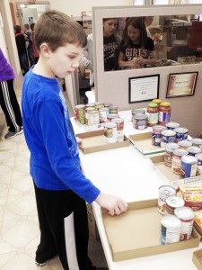 Photo by Micah Heddins Sullivan fifth grader Brett Johnson organizes canned goods at the Moultrie County food pantry Friday.