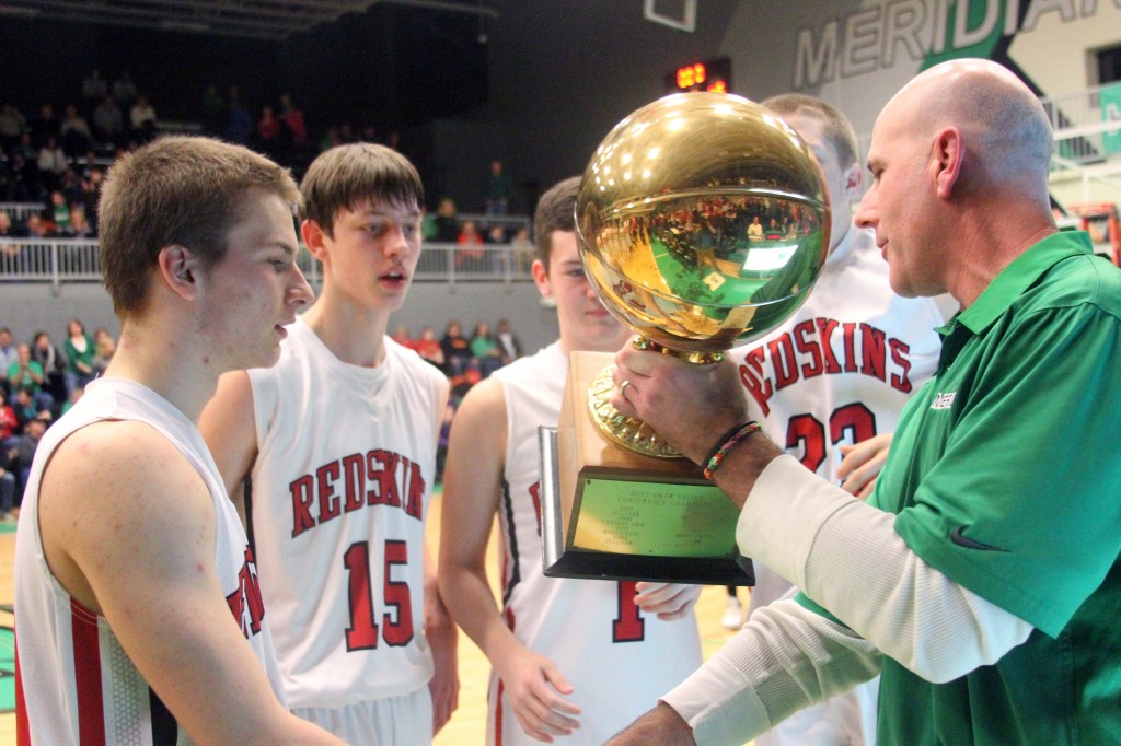 Photo by Keith Stewart Meridian athletic director Eric Hurelbrink hands Sullivan's four seniors the Okaw Valley Tournament championship trophy Saturday night after the Redskins beat Meridian 53-46.