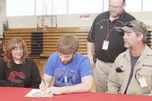 Photo by Keith Stewart SOV middle linebacker Walker Byers (center) signs his letter of intent to play football at Millikin University as his mother Melanie (left) and father, Luke (right) in addition to former head football coach Charles Brown (standing) watch during the April 9 ceremony at Sullivan High School.