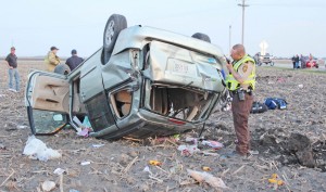 Photo by RR Best Moultrie County Deputy Sheriff Aaron Thomas calls in the license plate of a 2002 Mazda van after it flipped three times after exiting route 32 between Sullivan and Lovington Saturday evening. Two occupants were ejected from the vehicle. Both were life flighted to Carle Foundation Hospital in Urbana.