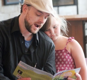 Photo by Keith Stewart John Golden reads his recently published children’s book “Kiley and the Love Struck Frog” as his daughter and inspiration for the book Kiley listens during Saturday morning’s public reading at Cathrine’s Custom Framing.