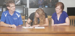 Photo by Keith Stewart Sullivan High School alumna Maggie Plank (center) signs her letter of intention to compete in volleyball at Omaha, Nebraska’s Grace University Friday May 30 as her father, Jim (left), and mother Lori (right) watch approvingly.