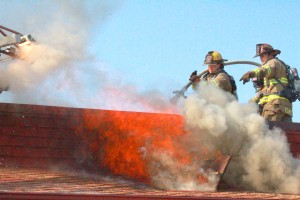 Photo by RR Best Sullivan firefighters Trevor Hughes and Larry Edwards stand atop the burning Red Apple restaurant Tuesday morning. 