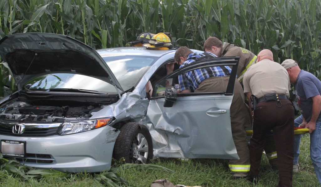 Photo by Keith Stewart Emergency personnel work to remove an elderly man from his vehicle Thursday afternoon east of St. Isidore church.