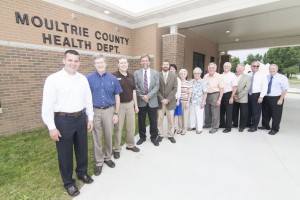 Photo by Keith Stewart The new Moultrie County Health Department facility was unveiled at an open house last month. Pictured in front of the new facility, from left to right, are: Ill. Rep. Adam Brown, board of health member Dr. Glen Dust, State Senator Chapin Rose’s chief of staff Landon Stenger, ADG, LTD architects Tim Raibley and Jason Wright, Moultrie County health department administrator Angela Hogan, board of health secretary Vickie Bowers, board of health members Marge Overlot and Kerry Pate, health department building committee chair Ron White, board of health member Mike Reedy, county board chairman Dave McCabe, and former director of the Coles County Regional Planning and Development Doug McDermand.