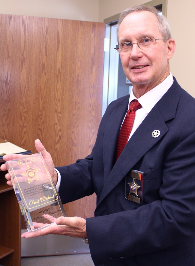 Photo by RR Best Outgoing sheriff Jeff Thomas holds a plaque congratulating him on his retirement at a public gathering in October.