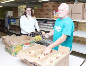 Photo by RR Best New Life members Lester Todd (right) and Sherry Smith (left) restocks shelves Friday morning at the ministry center.