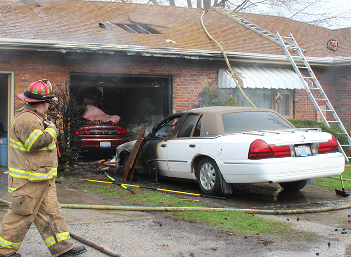 Photo by RR Best Sullivan fire captain Chris Wright looks at the remains of a vehicle fire that spread to a garage Wednesday afternoon.