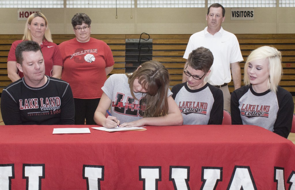 Photo by Keith Stewart Sullivan senior and basketball player Emily Neuhauser signs her letter of intent committing to play basketball at Lake Land College in an April 8 ceremony. Pictured, front row, left to right: Father John Neuhauser, Emily, mother Barb, and sister Paige. Back row: Sullivan girls’ head coach Sheri McCain, assistant coach Tiffinie Tucker, and Lake Land College girls’ head coach Dave Johnson.