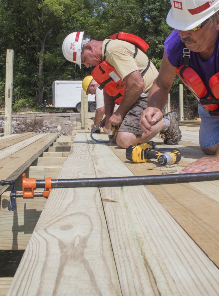 Photo by Keith Stewart Volunteer members from the Sullivan AmBucs install decking at the new fishing pier at Wood Lake. The pier was completed as of this week. The volunteers will next construct a roof for the pier.