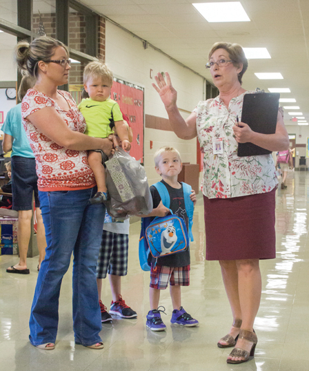 Photo by Keith Stewart Back to School at LGS Kindergartener Kade Ballinger stands next to his mother Melissa Nichols, who is seen holding her son Jace while school librarian Karen Smith-Cox gives directions last Wednesday, which marked the first day of school for ALAH CUSD 305.