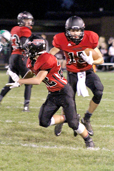 Photo by RR Best  Alec Ballinger (15) turns the corner getting protection from Drew Hubbard (22) as he racks up yardage on a great running night for the Redskins in their victory over the Meridian Hawks.