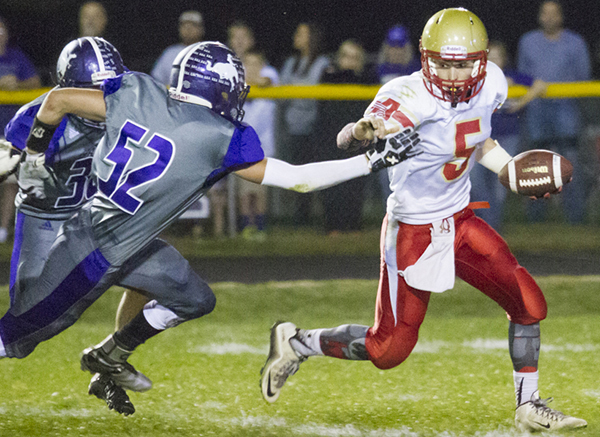 Photo by Keith Stewart ALAH quarterback Teddy Poe tries to evade Arcola’s Cole Hutton Friday night. This was a common sight as the Purple Riders’ defense constantly chased Poe out of the pocket en route to their 72-0 win over the Knights.