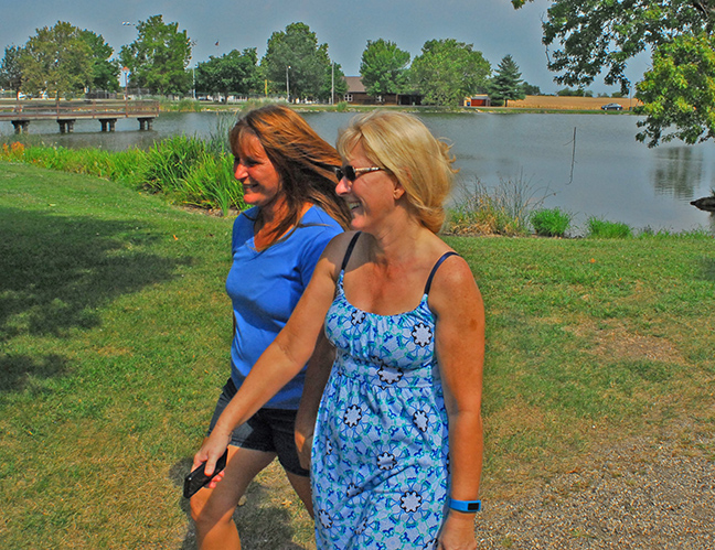 Photo by Mike Brothers Walking in the park is the same today as it was 100 years ago except the lake is a little bigger and the trees are mature. Sisters Martina Emrick and Teresa Ingram are taking a morning stroll around the lake on Wyman Park’s 100th birthday.