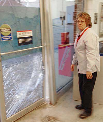 Photo by RR Best Post office clerk Trisha Elder inspects the damage last Tuesday after a car jumped the curb and crashed into the Sullivan Post Office lobby door.