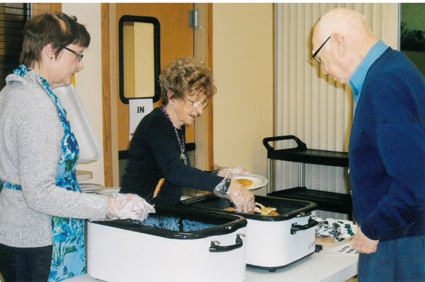 Photo furnished A Shrove Tuesday meal is being served 4:30-6 p.m. Fat Tuesday, Feb. 9 at First United Methodist Church in Sullivan. Elaine Daniels (left) and Fern Patton served Norm Buckner a plate of pancakes and sausage during the first Shrove Tuesday meal in 2015.