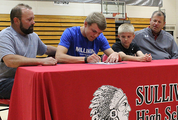 Photo by Mike Brothers Ballinger is Millikin Bound SHS athlete Alec Ballinger signed a letter of intent to play football for the  Millikin University Big Blue with teammates and students attending. Pictured from left: father Ed Ballinger, Alec, brother Aiden Ballinger and Sullivan High School head football coach Gerald Temples.