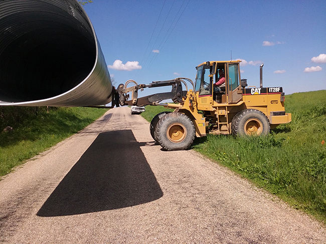 Photo furnished Culvert Replacement Sullivan Township Road Commissioner Elmo Weaver explained Moultrie County Road 1100N, south and east of Kirksville will need to be closed a couple days when weather permits. Then this drainage improving 50 foot long, six foot tall culvert can be installed. Above Township operator Rich Rutledge puts pressure on end loader tires as he unloads the five ton culvert, which was trucked from Kirksville, Missouri to Kirksville, IL.