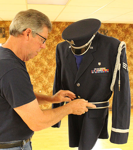 Photo by Mike Brothers Terry Muzzy prepares Honor Guard uniform that is part of the military memorabilia display at Bethany Celebration this weekend.