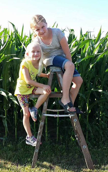 Photo furnished July Corn Cailyn, 9, and sister Cara,6, checked out the height of corn near Sullivan recently and found out it was a lot more than knee high in July. Cailyn and Cara are daughters of Eric and Candace Elder (SHS class of 1990) Murphy. Grandparents are Elvin and Leatitia Elder of Sullivan.