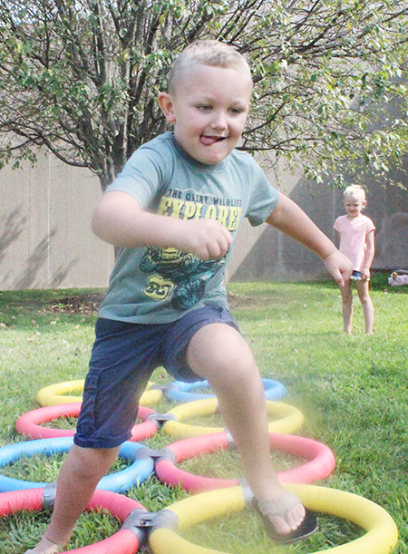 Photo by Mike Brothers Fun Time at Library Elizabeth Titus Library’s summer reading program added a little physical fun to the weekly story time and craft adventures last week. Above Asher Hendry, 5, races through rings on the library lawn August 3. 