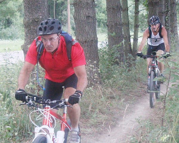 Photo by Mike Brothers CIMBA members Todd Harris (front) and Doug Lee of Sullivan ride a new section of the Camp Camfield trail in preparation for the Aug. 14 Clash at the Camp.