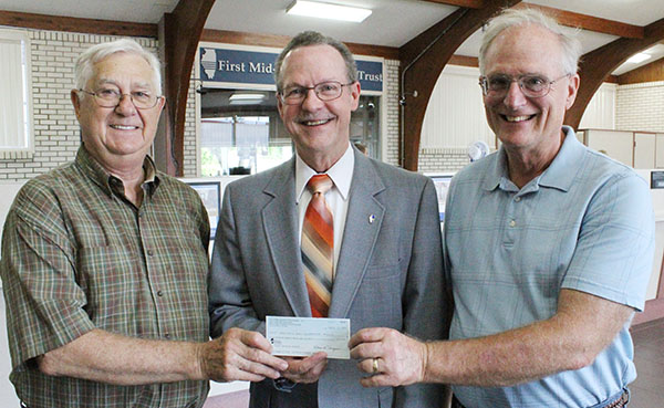 Photo furnished Early Pay Off The Moultrie County Board was able to make the final $64,583.33 payment on the county jail last week. Budget chairman Ron White noted the county was able to retire the $1 million loan 11 years early due to extra income generated through housing federal prisoners early on. Five county banks participated in the local debt certificate, accounting for the local share of financing for the jail. A $4 million grant helped finance the majority of the jail. Above Moultrie County budget chair Ron White (left) and Moultrie County Board chairman Dave McCabe (right) present First Mid Illinois Bank president Larry Stenger with the final payoff for the local loan.