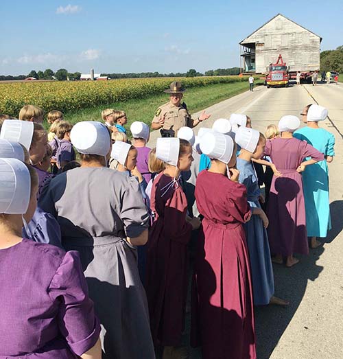 Photo furnished Illinois District 10 Trooper explains safety issues to Mennonite school children observing the move of the first Amish home in the state to the future Amish Heritage Center location last week.