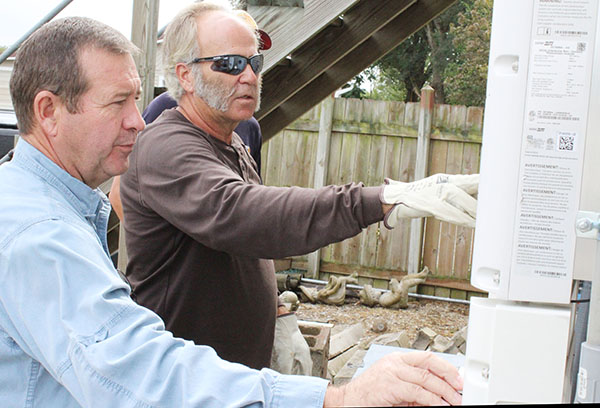 Photo by Mike Brothers Owner Mike Fowler, foreground, checks solar panel for connection while Sullivan utility lineman Kim Miller makes sure the connection to the city power grid is safe.