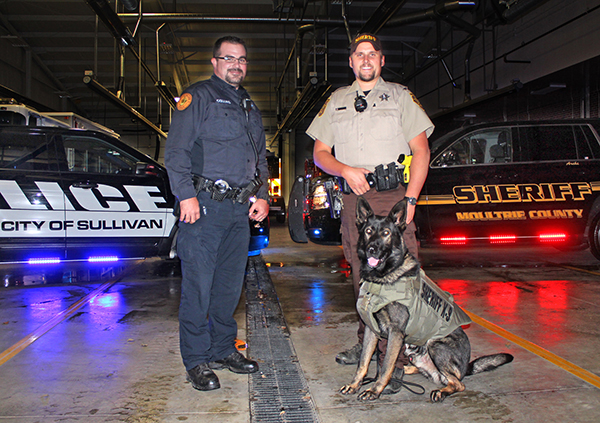 Photo by RR Best Archie Has Got a New Vest Sullivan patrolman Adam Collins and Moultrie County sheriff’s deputy Kaleb Smith, K-9 patrol Archie’s handler, is pictured with Archie in his new bullet and puncture proof vest. Sullivan police dept.’s annual Rushmore law enforcement golf outing generated the extra funds from the 50/50 raffle and hole sponsors to help purchase the new vest. Golf outing coordinator Collins received approval from the sheriff’s K-9 unit for the donation with which police were able to purchase the $1800 vest for $1100.