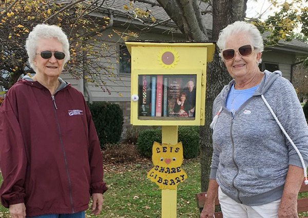 Photo By Ellen Ferrera Lending Library at Mason Point Judith Brown (l) and Jean Dulik visit the little lending library at Mason Point. Ellen Dick-Ferrera, former librarian, with some help from friends at the Senior Center established the free lending library at Mason Point earlier this year. Visitors can rest on the bench and read books from the box or borrow them to bring back later. Located along a popular walking route, people living in the duplexes can take a book or leave a book, with eveyone sharing from the little library.  Ferrera hopes to eventually include books from the main library and share magazines as well. 