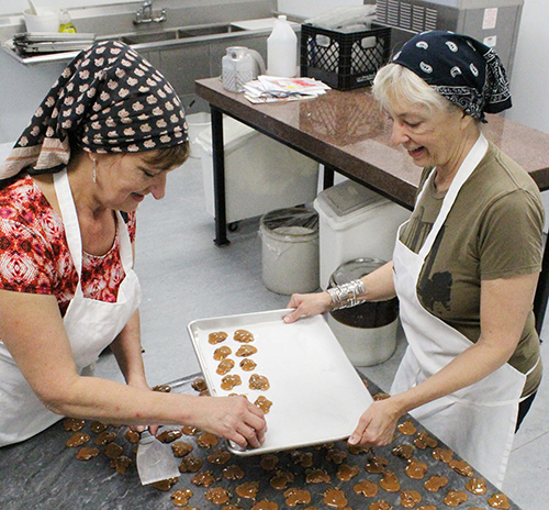 Photo by Mike Brothers Flesor Candy Kitchen owners (from left) Devon and Ann place Paul’s Pecan Favorites before packaging. The “turtle style treat” has been a Candy Kitchen favorite since Grandfather Gus created it back in 1901.