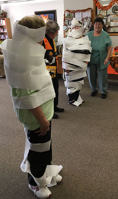 Photo by Ellen Ferrera Mummy wrap was popular during the Halloween party as two teams competed against time to wrap their partners into a mummy with rolls of toilet paper.