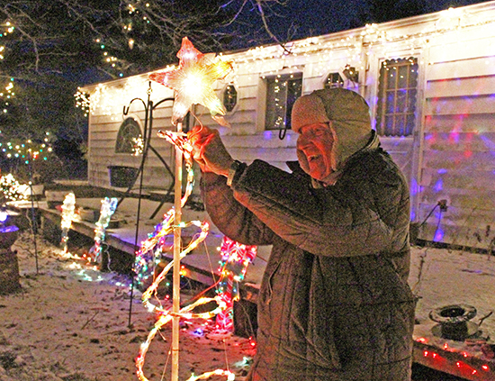 Photo by Mike Brothers Paul Feist has decorated his home southeast of Sullivan since 1959. Above he puts the finishing touches to the display that may be seen from the city limits.